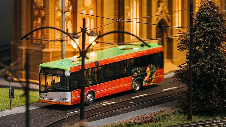 Ein Modellbus im Advents-Design fährt durch eine Modellstadt