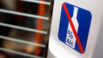 Aufkleber in einer Stadtbahn, der eine durchgestrichene Alkoholfalsche auf blauem Hintergrund zeigt.