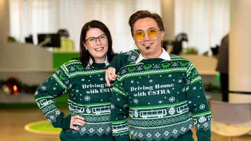 Eine Frau und ein Mann tragen denn "ugly christmas sweater" der ÜSTRA aus dem Jahr 2025.