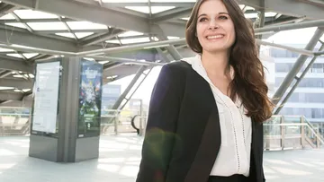 Frau im Business Outfit an Haltestelle