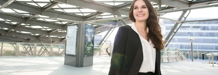 Frau im Business Outfit an Haltestelle