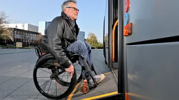 Ein Rollstuhlfahrer fährt über die Rampe in einen Bus ein.