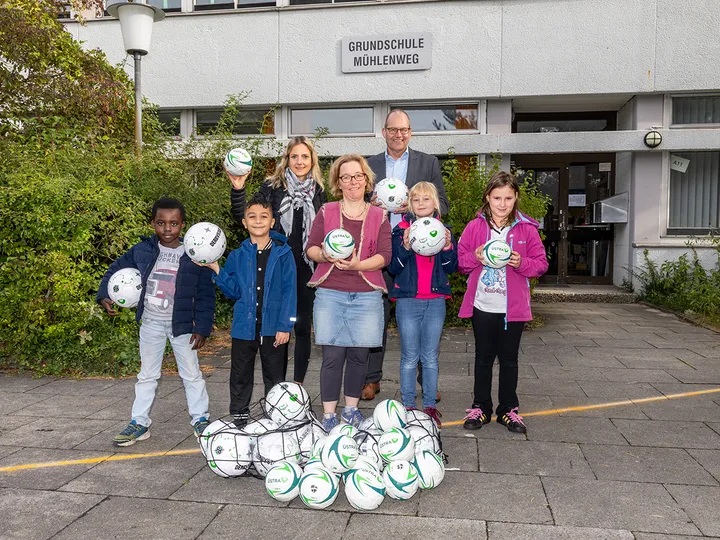 Die ÜSTRA Vorständin Elke Maria van Zadel und Ulf Birger Franz übergeben der Schulleitung und den Kindern der Grundschule die Bälle