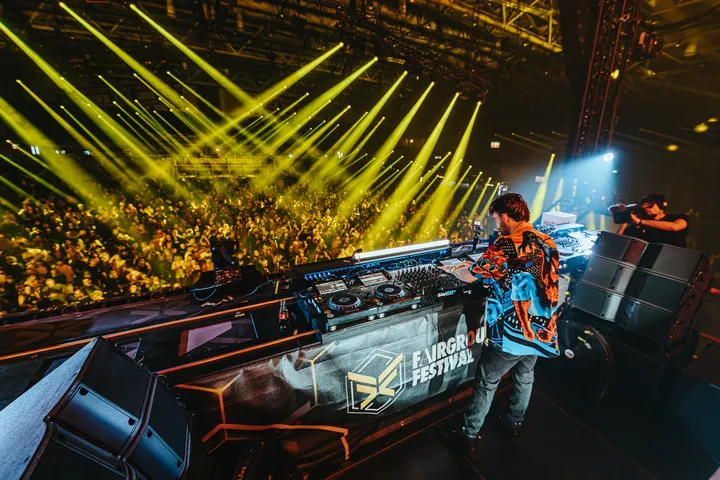 DJ steht in Messehalle bei einem großen Festival mit vielen Besuchern