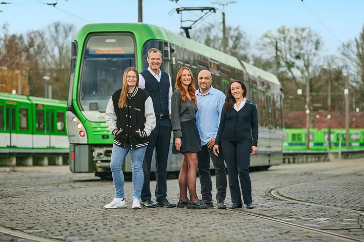 Mehrere Mitarbeitende der ÜSTRA stehen vor einer Stadtbahn.
