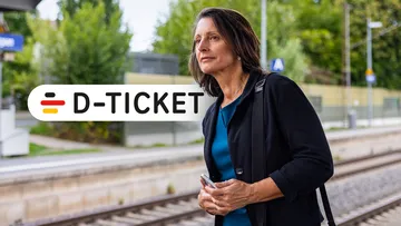 Berufstätige Frau mit Deutschland Jobticket steht am Gleis und wartet auf ihre Bahn