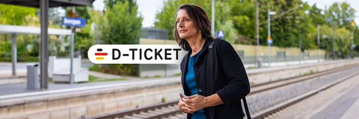 Berufstätige Frau mit Deutschland Jobticket steht am Gleis und wartet auf ihre Bahn