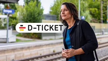 Berufstätige Frau mit Deutschland Jobticket steht am Gleis und wartet auf ihre Bahn