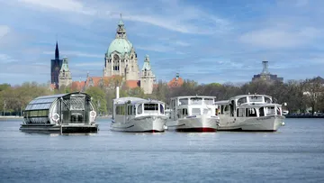 Die vier Boote der Maschseeflotte nebeneinander auf dem Wasser, im Hintergrund die Skyline von Hannover mit dem neuen Rathaus.