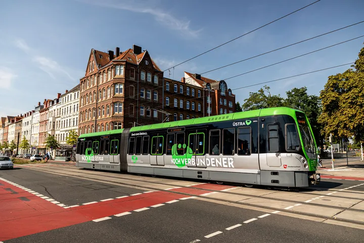 Ein fahrender T W 3000 mit einer großen Beklebung an der Seite. Auf der Beklebung steht "noch verbundener" und das ÜMO.