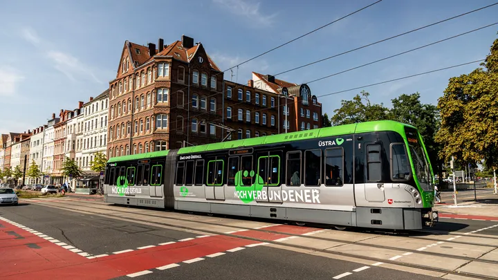 Ein fahrender T W 3000 mit einer großen Beklebung an der Seite. Auf der Beklebung steht "noch verbundener" und das ÜMO.