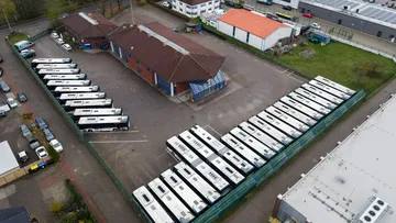 Eine Luftaufnahme des Betriebshofes Mellendorf. Um ein Backsteingebäude stehen Busse nebeneinandergereiht.