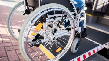 Nahaufnahme der Räder eines Rollstuhls, der über eine Rampe in einen Bus fährt