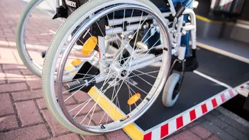 Nahaufnahme der Räder eines Rollstuhls, der über eine Rampe in einen Bus fährt