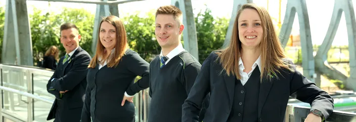 ÜSTRA Mitarbeitende in Dienstkleidung stehen aufgereiht an Geländer