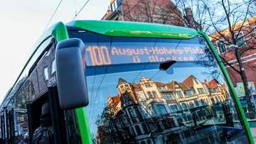 Ansicht einer Front des Stadtbusses der Linie 100 in der Scheibe spiegeln sich Fachwerhäuser bei sonnigem Winterwetter