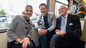 ÜSTRA Vorständin van Zadel, Regionspräsident Krach und der ehemalige Oberbürgermeister Schmalstieg sitzen in einer Stadtbahn und lächeln in die Kamera.