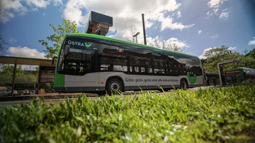 Ein Elektrobus der Marke Mercedes steht am August-Holweg-Platz in Hannover. Der Bus lädt gerade die Batterien über die Ladesäule auf. Auf dem Bus ist eine Werbung mit dem Slogan "Grün, grün, grün, sind alle meine Fahrten!" angebracht.