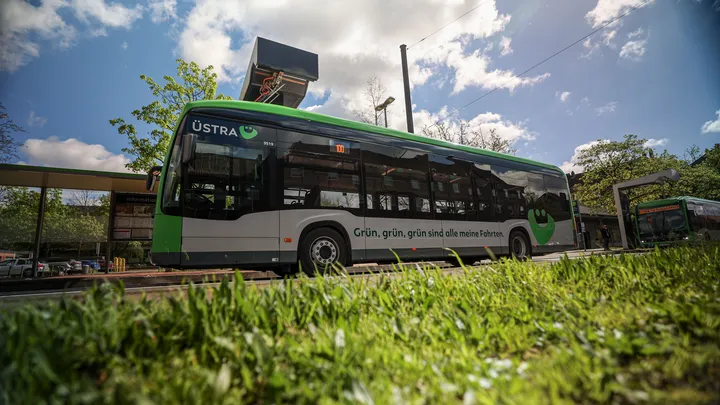 Ein Elektrobus der Marke Mercedes steht am August-Holweg-Platz in Hannover. Der Bus lädt gerade die Batterien über die Ladesäule auf. Auf dem Bus ist eine Werbung mit dem Slogan "Grün, grün, grün, sind alle meine Fahrten!" angebracht.