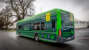 Das Winterdesign der ÜSTRA 2025 ist in einem Strickmuster gehalten. Ein Bus wurde damit vollflächig beklebt. Auf dem Bild sieht man das Heck und die Seitenansicht des Busses.