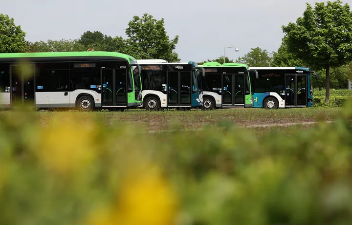 Vier Busse stehen hintereinander versetzt auf einem Betriebshof.