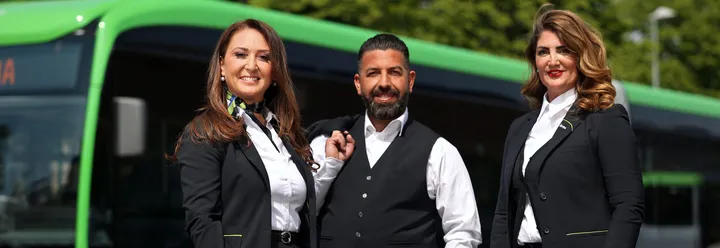 Drei ÜSTRA Mitarbeitende posieren vor Stadtbus in Dienstkleidung