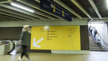Ein großes gelbes Schild in der Station Steintor. Es zeigt einen Pfeil nach unten links und verweist auf die Linien 4, 5, 6 und 11 mit den jeweiligen Endpunkten Roderbruch, Anderten, Messe/Ost und Zoo. Die Linienwege sind daneben schematisch dargestellt.