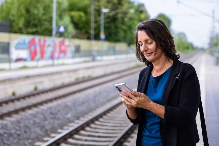 Frau steht auf einem S-Bahnhof in Wennigsen und schaut auf ihr Handy.