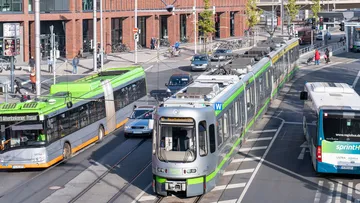 Abgebildet sind von den Verkehrsunternehmen ÜSTRA und regiobus zwei Busse und eine Stadtbahn in der Innenstadt/ZOB von Hannover